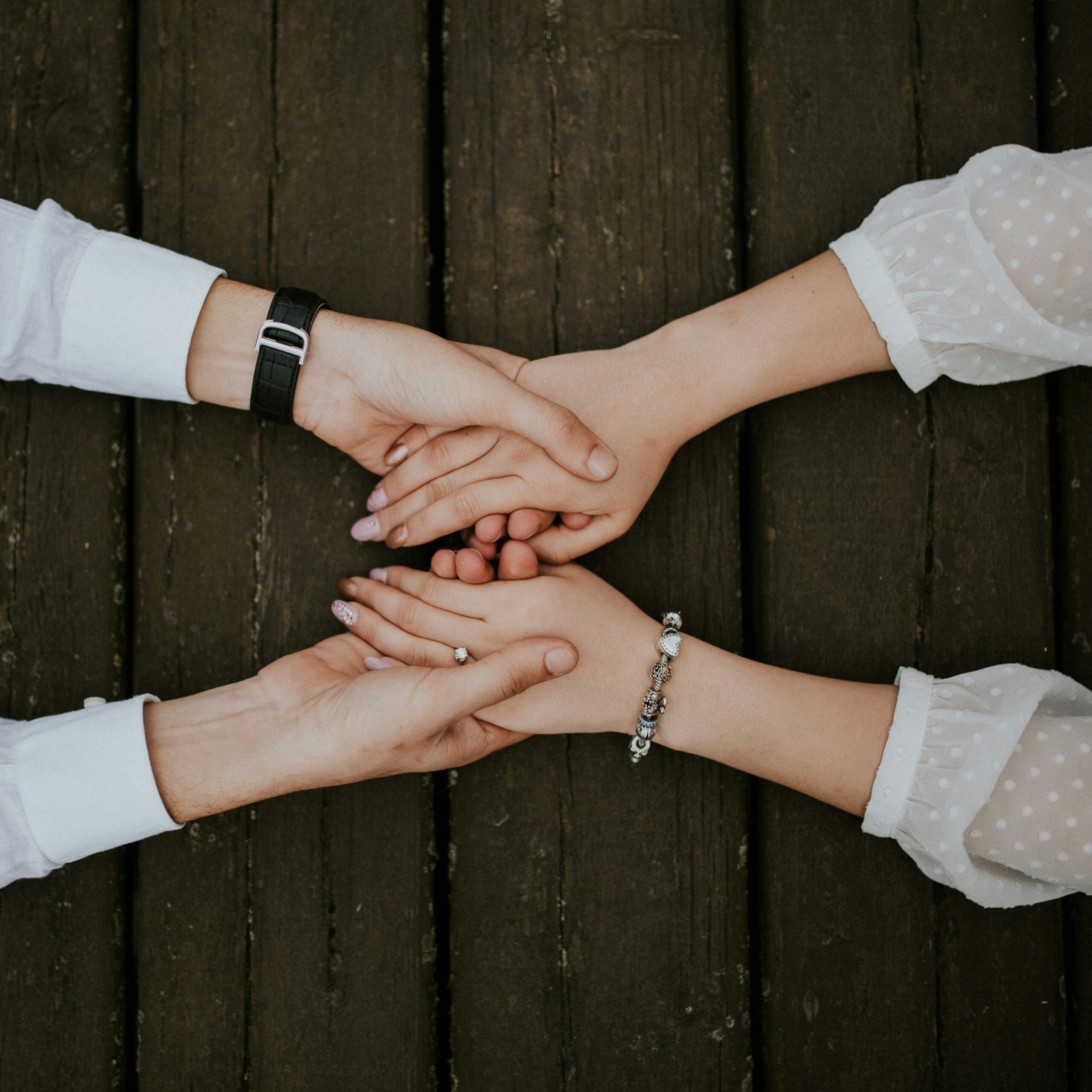 Two people holding hands over a wooden table