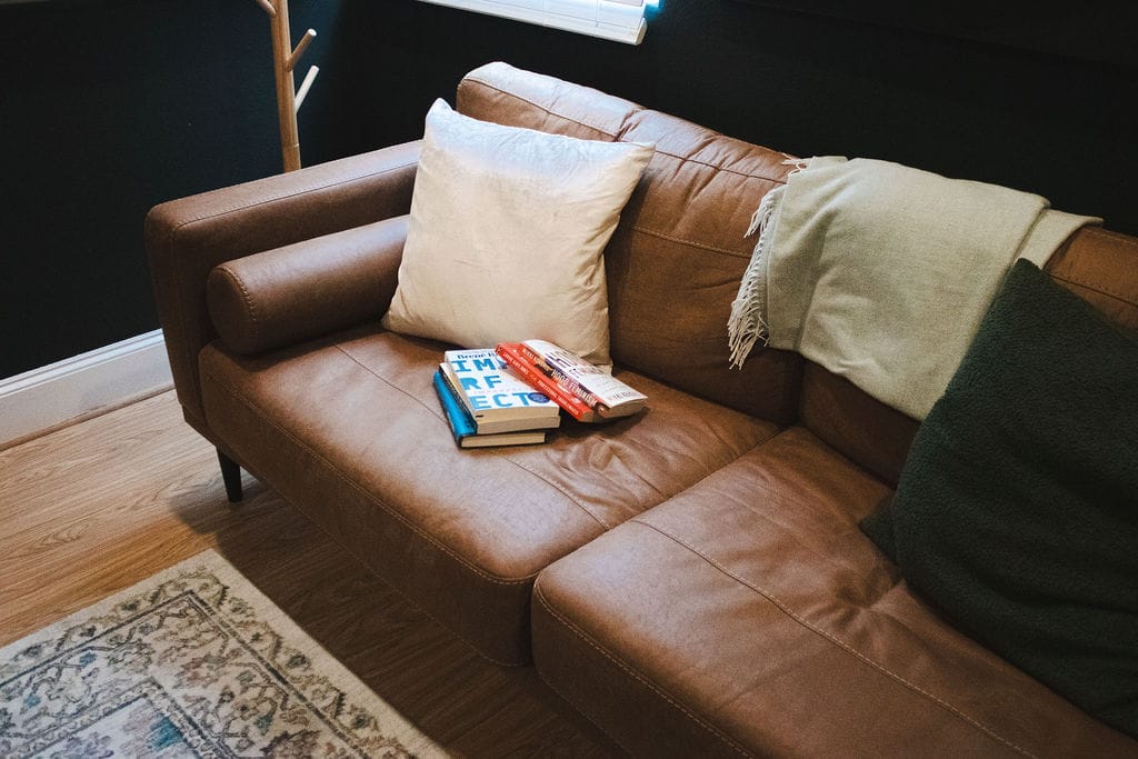 Tan sofa with cushions and a throw in a Social House counseling room.