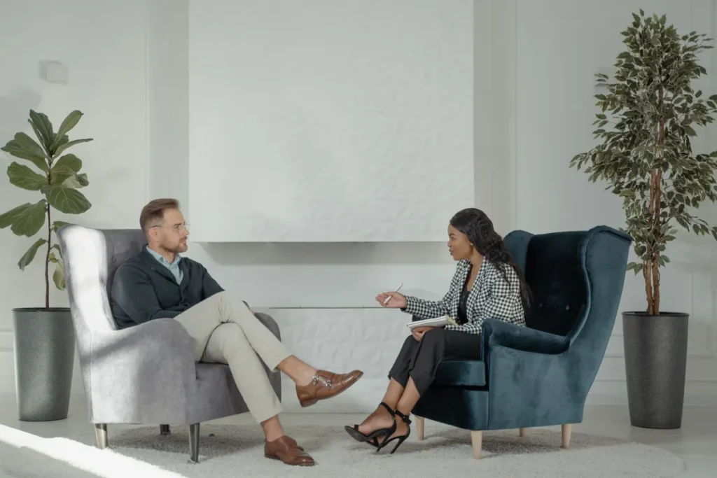 Two adults seated in armchairs having a conversation